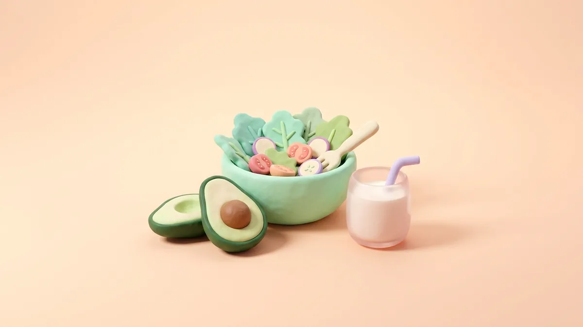 A 3D clay bowl of salad, an avocado and a glass of milk on a soft peach background